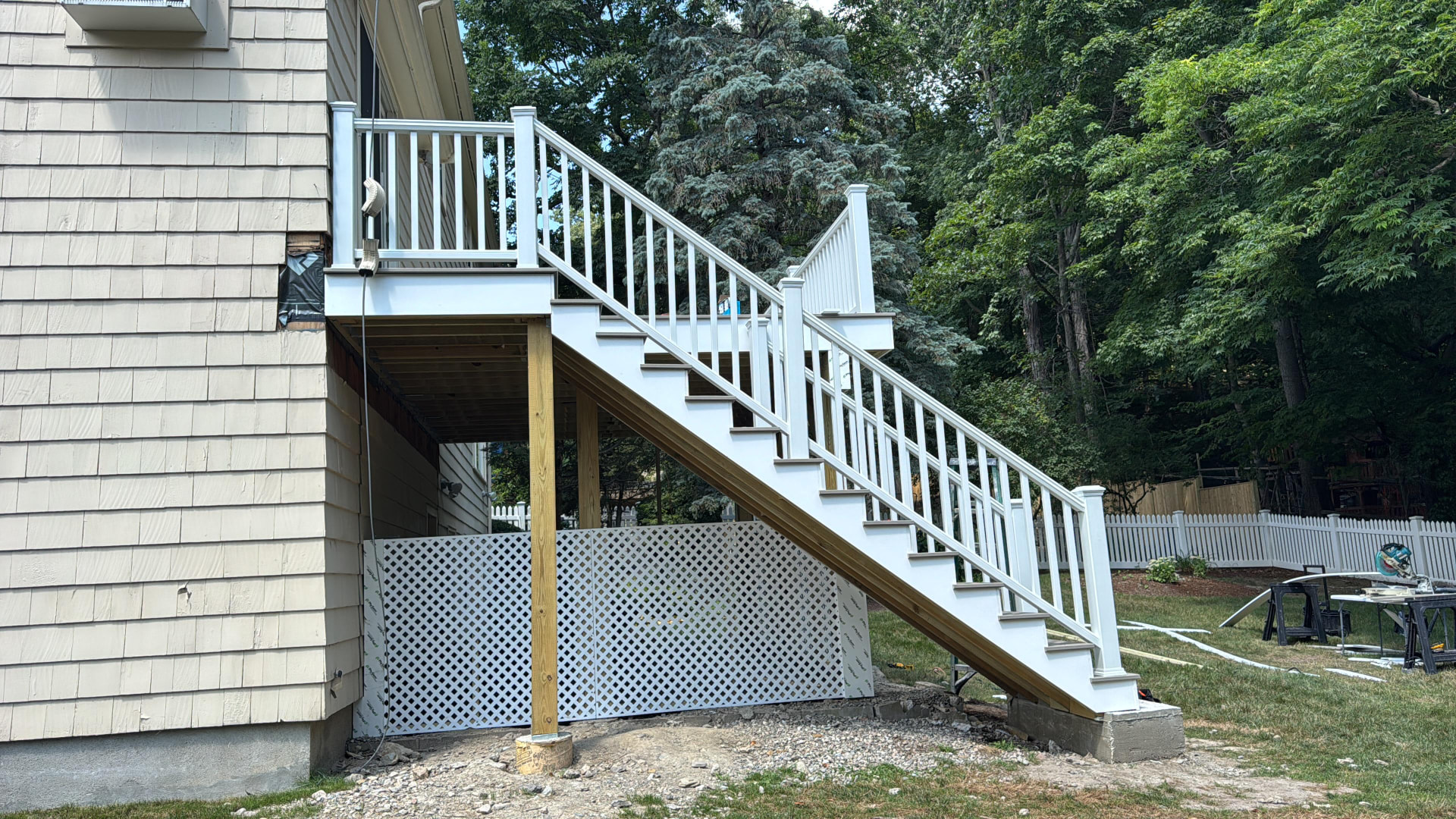 Exterior deck stairs with white railings and lattice skirting