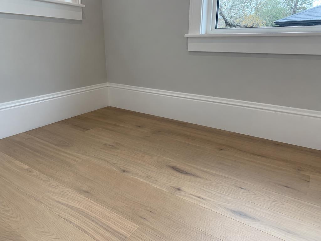 White baseboard molding installed along a gray wall